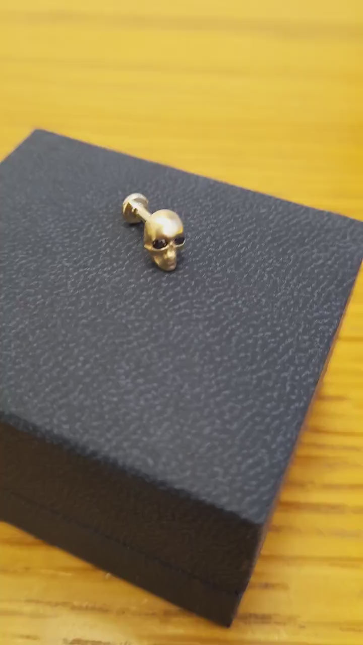 unique and edgy skull stud earring is adorned with black diamonds, crafted with a matte finish.